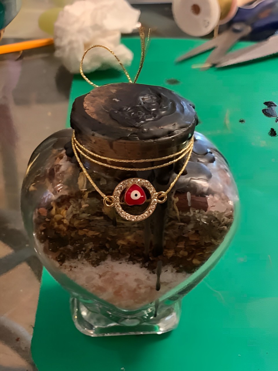 A Glass Jar With a Gold Chain and a Striking Red Eye Inside